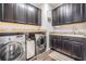 Well-equipped laundry room with dark cabinetry, granite countertops, and modern washer and dryer units for convenience at 17724 Daisy Farm Dr, Lutz, FL 33559