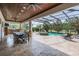 Covered outdoor dining area overlooking the pool with a slide, spa, and lush landscaping at 17724 Daisy Farm Dr, Lutz, FL 33559