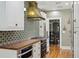 Bright kitchen featuring white cabinets, wood countertops, colorful backsplash, and stainless steel appliances at 2511 W Morrison Ave, Tampa, FL 33629