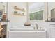 Bathroom featuring a garden tub with tile surround, a double vanity, and natural light from the window at 30410 Ceasar Park Dr, Wesley Chapel, FL 33543
