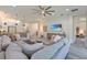 Open living room with gray wood floors, a large sectional couch, and an entertainment center with beach decor at 30410 Ceasar Park Dr, Wesley Chapel, FL 33543