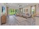 Spacious living room features gray wood floors and a large sectional couch with access to the outdoor patio at 30410 Ceasar Park Dr, Wesley Chapel, FL 33543