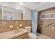 Cozy bathroom featuring brown tiling, a vanity with sink, toilet, and shower with shower curtain and grab bar at 3547 Odom Dr, New Port Richey, FL 34652