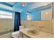 Retro blue bathroom featuring a vanity, mirror, toilet, and tub with a window providing natural light at 3547 Odom Dr, New Port Richey, FL 34652