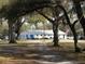 View of the clubhouse surrounded by mature trees and a paved pathway at 37229 Lois Ave, Zephyrhills, FL 33542