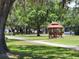 Community gazebo featuring a red roof and matching benches in a large grassy area at 37229 Lois Ave, Zephyrhills, FL 33542