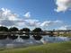 A serene pond reflects the surrounding houses, trees, and sky with scattered clouds at 37229 Lois Ave, Zephyrhills, FL 33542