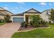 Charming single-story home featuring a brick driveway, a blue garage door, and meticulously landscaped front yard at 3972 Wisdom Trl, Land O Lakes, FL 34638