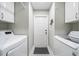 Functional laundry room with white cabinets, machines, and a door to the outside at 423 Fan Palm Ne Ct, St Petersburg, FL 33703
