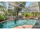 Screened-in pool featuring a brick surround and landscaped planters on raised steps at 423 Fan Palm Ne Ct, St Petersburg, FL 33703