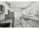 Galley kitchen with granite counters, stainless appliances and modern white cabinets at 4608 Deltona Blvd, Spring Hill, FL 34606