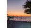 Picturesque beachfront scene at sunset featuring a pier, chairs, and a palm tree silhouette at 5529 White Marlin Ct, New Port Richey, FL 34652