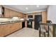 Efficient kitchen with wooden cabinets, black appliances, a breakfast bar, and tile flooring at 5705 Baywater Dr # 5705, Tampa, FL 33615