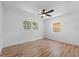 A clean, vacant bedroom with hardwood floors, two bright windows, and a ceiling fan at 7137 Wedgewood Dr, New Port Richey, FL 34652