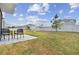 Wide backyard view featuring a patio with two black chairs on the right, a playset, and a white fence at 7380 Sail Clover Ln, Zephyrhills, FL 33540