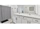 Well-lit bathroom featuring double vanity with white cabinets and modern fixtures, complemented by a patterned shower curtain at 7380 Sail Clover Ln, Zephyrhills, FL 33540