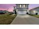 Contemporary two-story home with a long driveway and an attached two-car garage at 7380 Sail Clover Ln, Zephyrhills, FL 33540