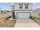 Inviting home featuring a two-car garage, landscaping, and a walkway to the front door at 7380 Sail Clover Ln, Zephyrhills, FL 33540