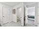 Bright hallway featuring tile floors, an open doorway to a bedroom, a nearby door to the toilet, and a storage grid at 7380 Sail Clover Ln, Zephyrhills, FL 33540