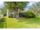A green backyard with lush grass, mature trees, screened-in patio, and a two-story home at 7412 Bridgeview Dr, Wesley Chapel, FL 33545