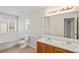 Bathroom featuring double sinks, a large mirror, and a bathtub with tiled surround at 7412 Bridgeview Dr, Wesley Chapel, FL 33545