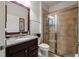Elegant bathroom with granite countertop, cherry-stained cabinets, glass shower, and decorative mirror at 7912 Yale Harbor Dr, Wesley Chapel, FL 33545