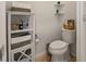 Small powder room with tile floors featuring a cabinet, corner shelves, and toilet with a basket at 7912 Yale Harbor Dr, Wesley Chapel, FL 33545