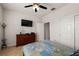 Bedroom with tiled floors featuring a tv, dresser, fan, and queen bed with a patterned comforter at 7912 Yale Harbor Dr, Wesley Chapel, FL 33545
