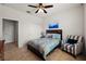 Bright bedroom with tan tiled floors, ceiling fan, queen bed, and sitting chair near the window at 7912 Yale Harbor Dr, Wesley Chapel, FL 33545