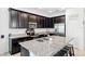 Modern kitchen features granite countertops, dark cabinetry, stainless steel appliances, and a functional kitchen island at 8496 Starlight Loop, Parrish, FL 34219