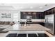 Open-concept kitchen with dark cabinets, granite island with barstool seating, and stainless steel appliances and open to living area at 8496 Starlight Loop, Parrish, FL 34219