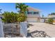 Charming two-story home with blue shutters, a white picket fence, and a spacious driveway at 1210 Bay Pine Blvd, Indian Rocks Beach, FL 33785