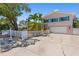 Inviting two-story home with well-kept landscaping, a white fence, and a large driveway at 1210 Bay Pine Blvd, Indian Rocks Beach, FL 33785