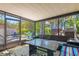 Relaxing screened porch features comfortable seating, a dining table and views of the lush backyard at 1210 Bay Pine Blvd, Indian Rocks Beach, FL 33785