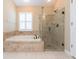 Bathroom features a tub, glass shower, neutral tones, and window shutters at 12204 Coldstream Ln, Tampa, FL 33626
