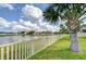 Scenic backyard featuring a lush lawn, a classic white picket fence, and serene water views at 13111 Bahia Grass Ln, Riverview, FL 33579