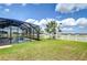 Lovely view of screened-in pool, a white picket fence, and green grass in a tranquil backyard setting at 13111 Bahia Grass Ln, Riverview, FL 33579