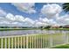 Scenic view of the pond from the backyard, enhanced by a white picket fence at 13111 Bahia Grass Ln, Riverview, FL 33579