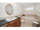 Bright bathroom featuring a soaking tub, tiled surround, granite counters, and a decorative oval mirror at 14175 Feather Sound Dr, Clearwater, FL 33762