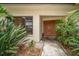 Elegant front entrance with double doors, surrounded by tropical plants and decorative landscaping at 14175 Feather Sound Dr, Clearwater, FL 33762