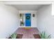 Covered front porch with brick flooring, blue front door with wreath, and decorative plants at 15604 Deerglen Dr, Tampa, FL 33624