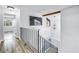 Bright hallway with wood floors, black metal railing, and natural light from windows and doors at 15604 Deerglen Dr, Tampa, FL 33624