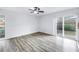 Bright, open living room with wood floors, ceiling fan, and sliding glass door to the backyard at 15604 Deerglen Dr, Tampa, FL 33624