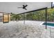 Large screened in patio with two ceiling fans and stone pavers beside the pool and tropical plants at 15604 Deerglen Dr, Tampa, FL 33624