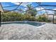 A screened-in pool area features a stone paver deck, waterfall feature, and lush tropical landscaping at 15604 Deerglen Dr, Tampa, FL 33624