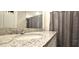 Granite countertop with double sinks and mirrors with a shower and gray shower curtain in the background at 17015 Coral Key Dr, Nokomis, FL 34275