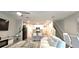 An open-concept living room with an eat-in kitchen, dining area, white couches, glass tables, and stairs at 17015 Coral Key Dr, Nokomis, FL 34275