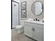 Contemporary bathroom with a walk-in shower, sleek vanity, round mirror, and modern fixtures at 17420 Moonflower Dr # 203, Venice, FL 34293
