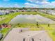 A beautiful aerial view of the community pond with lush landscaping, a playground, and a glimpse of the neighborhood at 17618 Cortes Creek Blvd, Spring Hill, FL 34610
