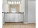 Bathroom featuring double vanity with white cabinets, granite counters, wood-look tile flooring and framed mirror at 17618 Cortes Creek Blvd, Spring Hill, FL 34610